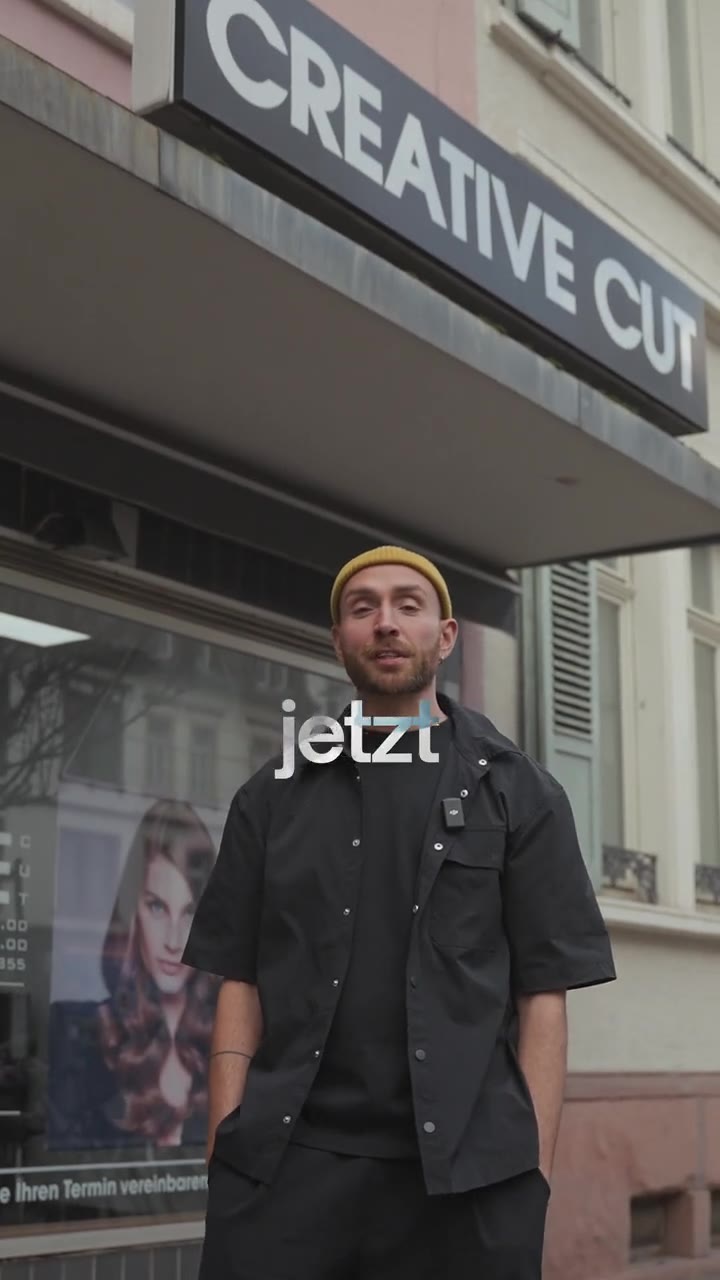 Vorschau: Friseur mit gelber Mütze vor dem Salon Creative Cut.